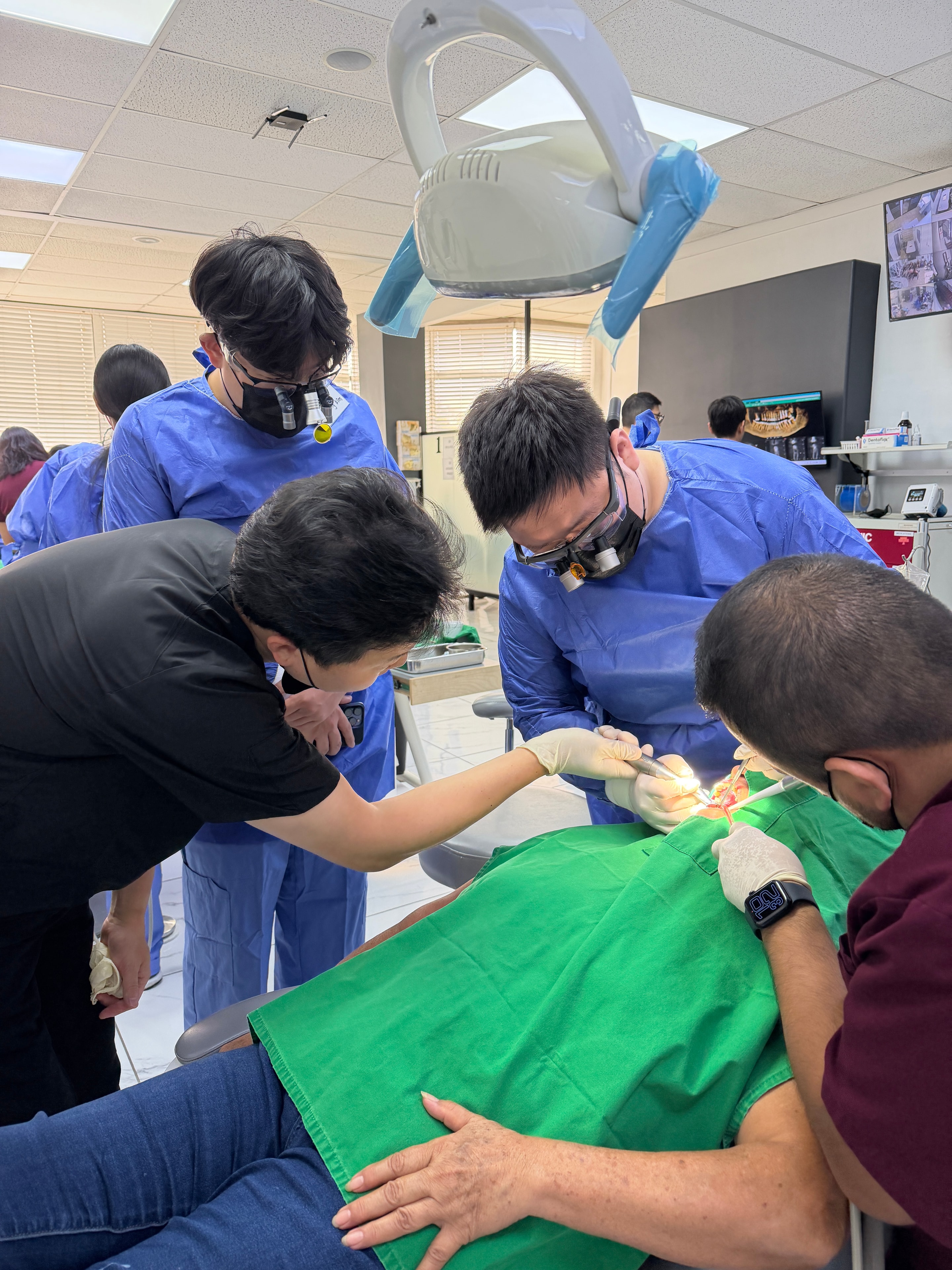 Faculty and participants observing live implant surgery procedure during the course