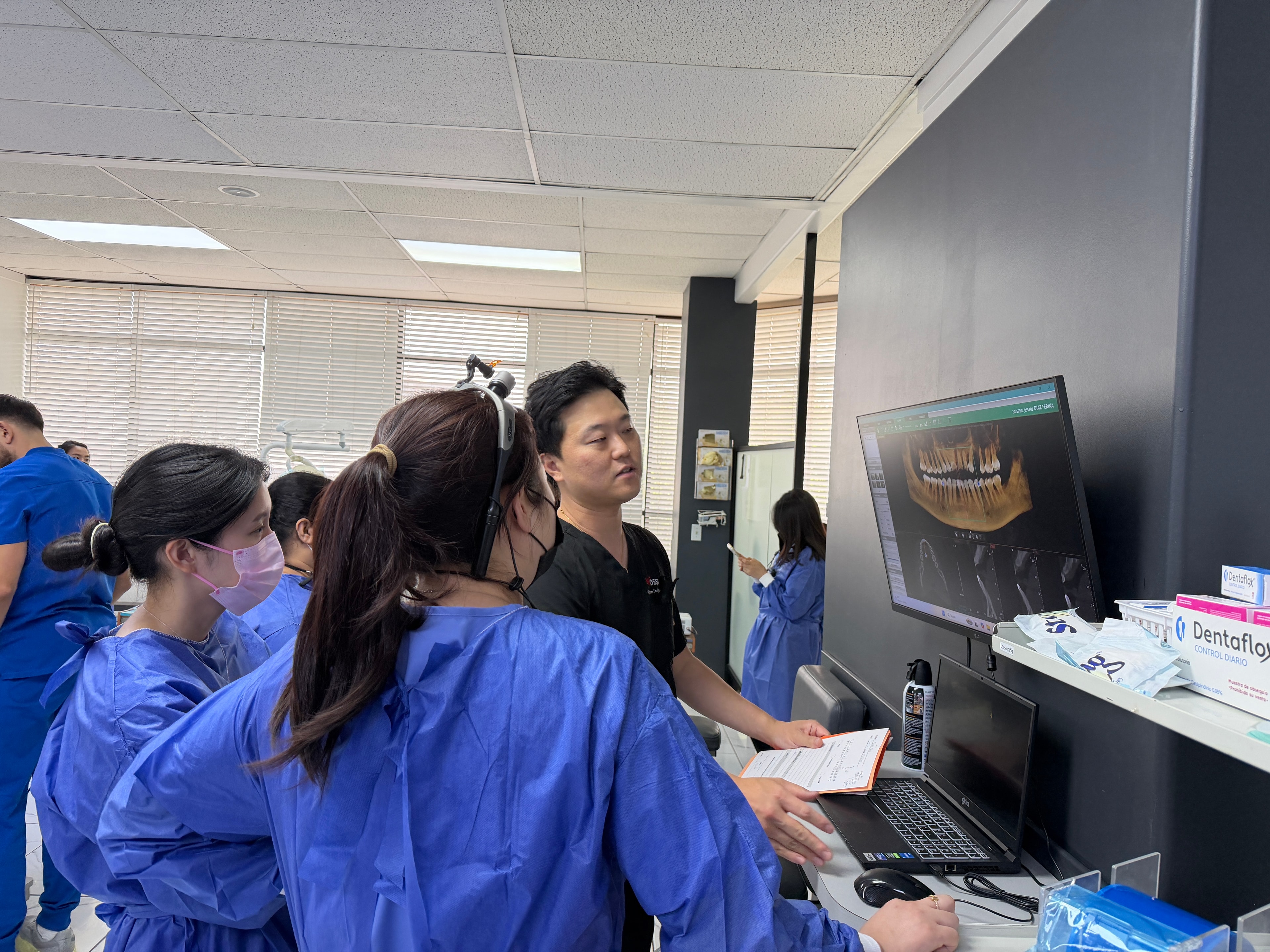 Faculty overseeing implant placement procedure with course participants